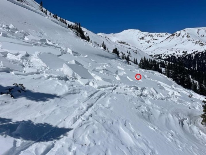<b>Figure 6:</b> Worker 1's track entering the side of the avalanche. The red circle marks the approximate location where Worker 1 triggered the avalanche. The slope angle near the red circle is between 20 and 25 degrees. The slope angle near the crown in the left of the image is 30 up to 35 degrees. (Image taken April 9, 2024). (<a href=javascript:void(0); onClick=win=window.open('https://classic.avalanche.state.co.us/caic/media/full/acc_876_52632.jpg','caic_media','resizable=1,height=820,width=840,scrollbars=yes');win.focus();return false;>see full sized image</a>)